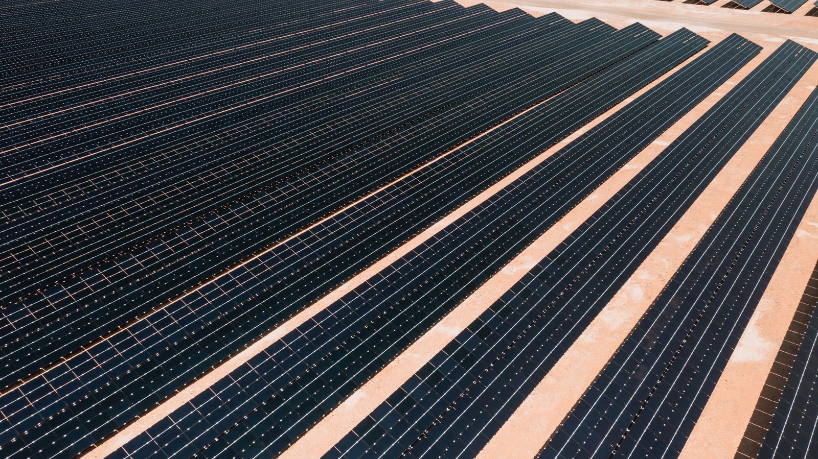 Rows of solar panels stretching to the horizon under a clear sky
