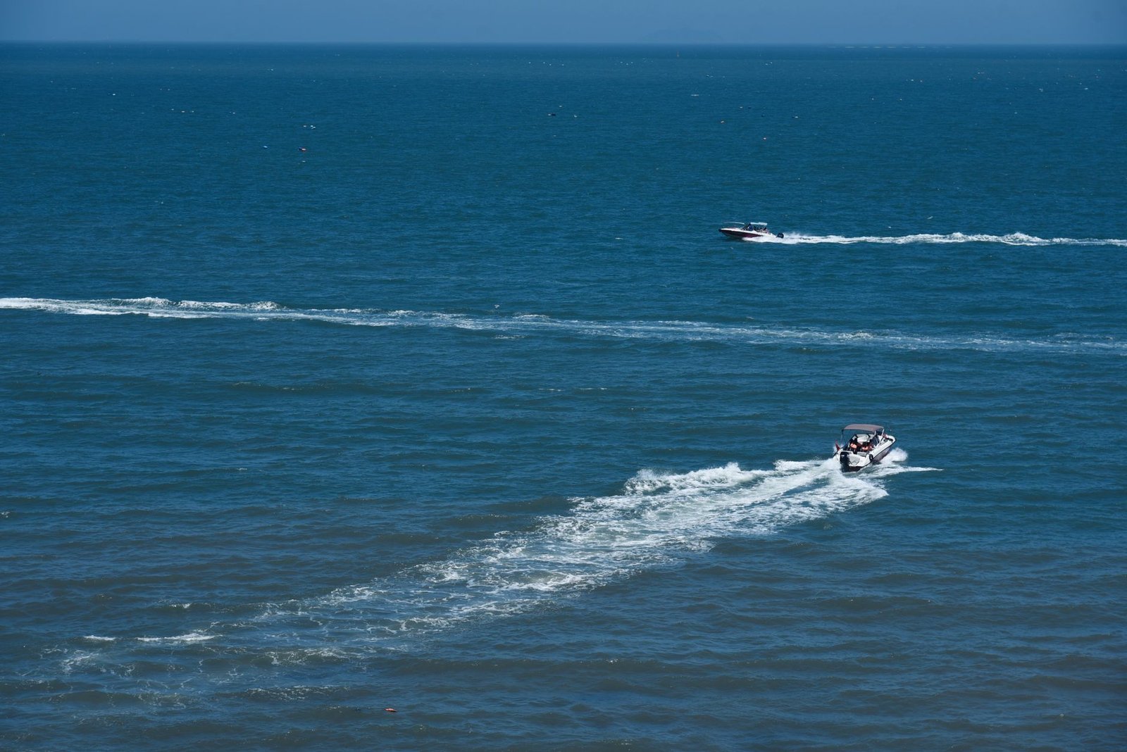 A conventional planing motorboat throwing a large bow wave at speed