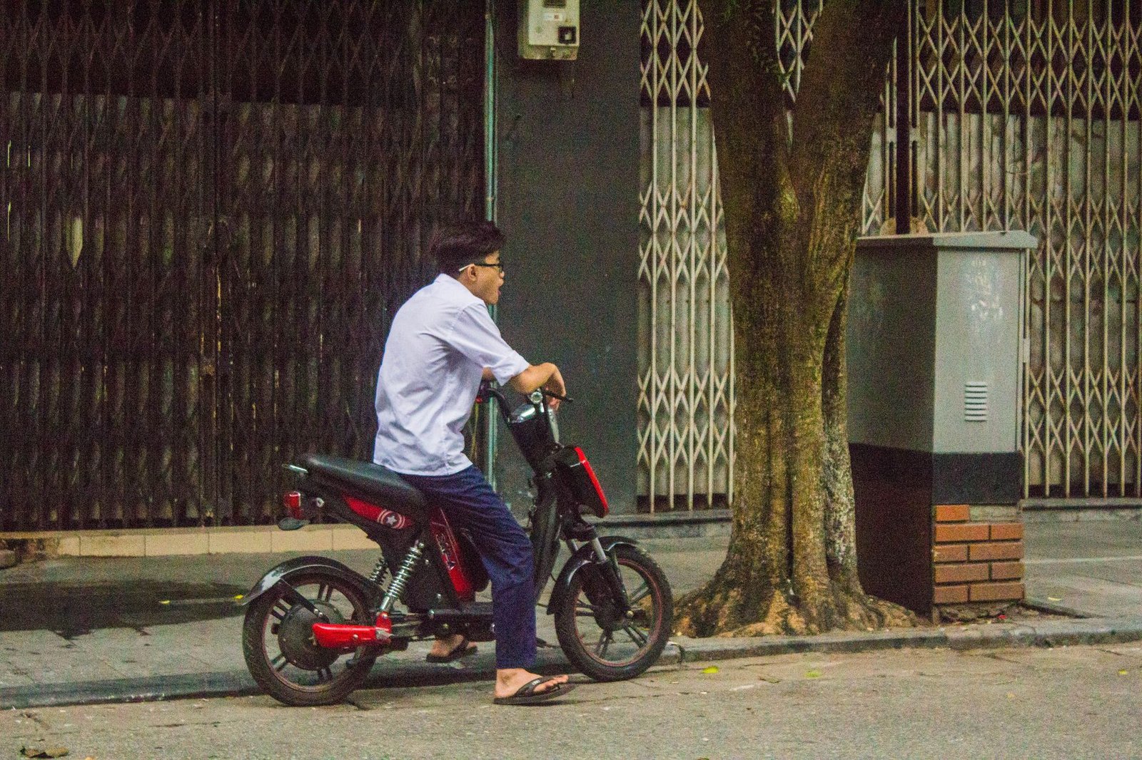 Electric scooters parked along a busy city street in Asia