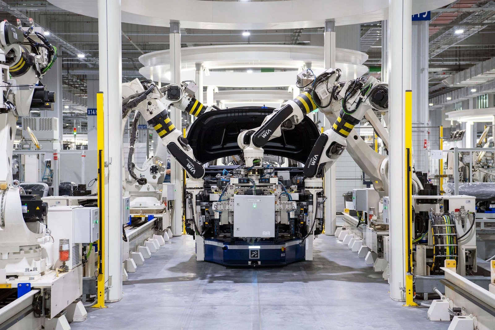 An electric vehicle assembly line in a modern Chinese car factory, vehicle bodies moving along the production line
