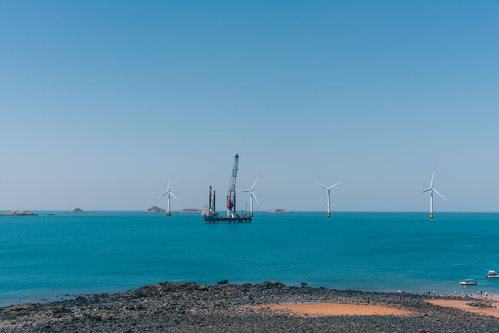 An offshore wind farm under construction, an installation vessel raising a turbine