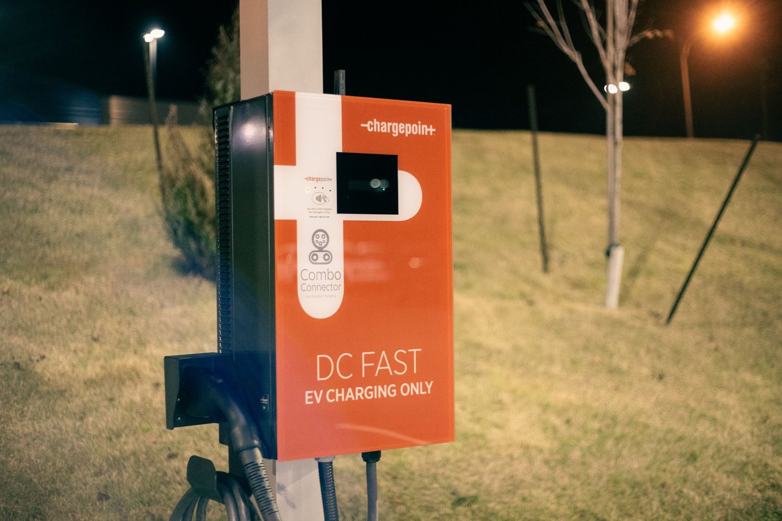 An electric-vehicle DC fast-charging station with several charging units, cables coiled at each stall