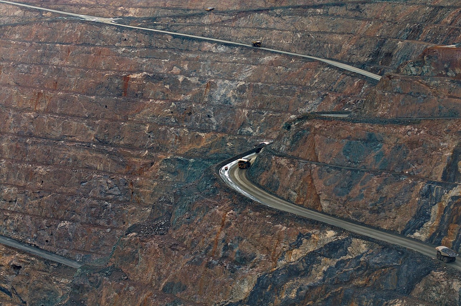 An open-pit iron ore mine with haul roads cut into the terraces
