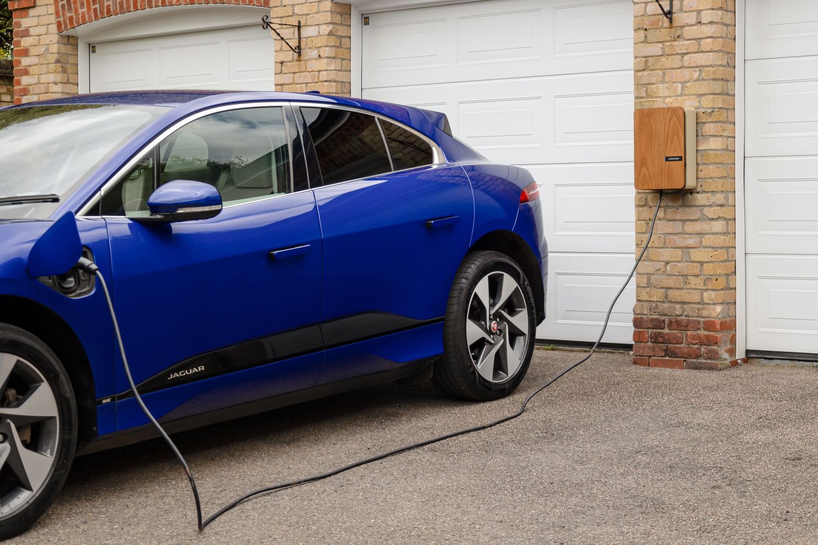 An electric car charging on a home charger in a driveway